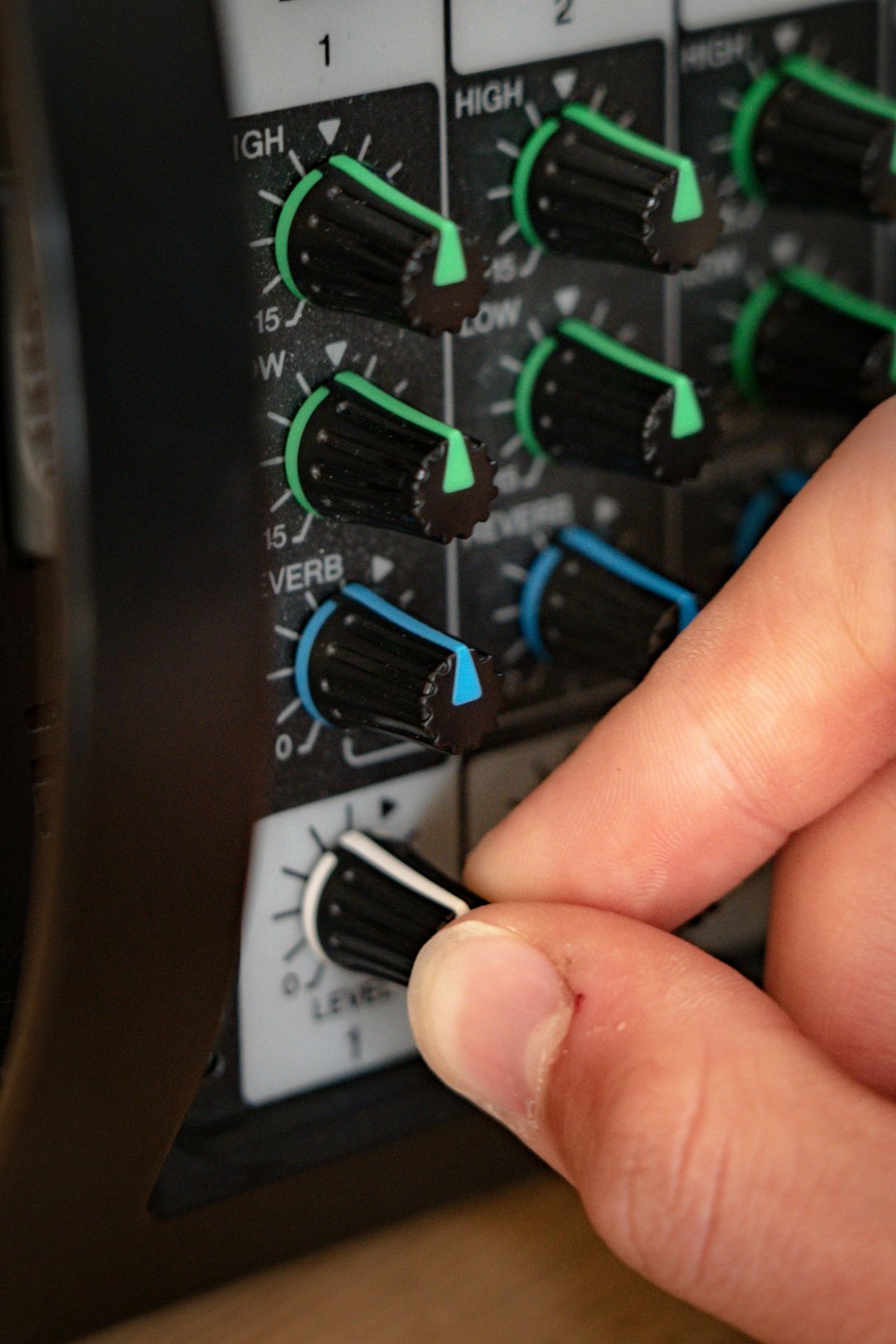 A hand turns a knob on a professional audio mixer.