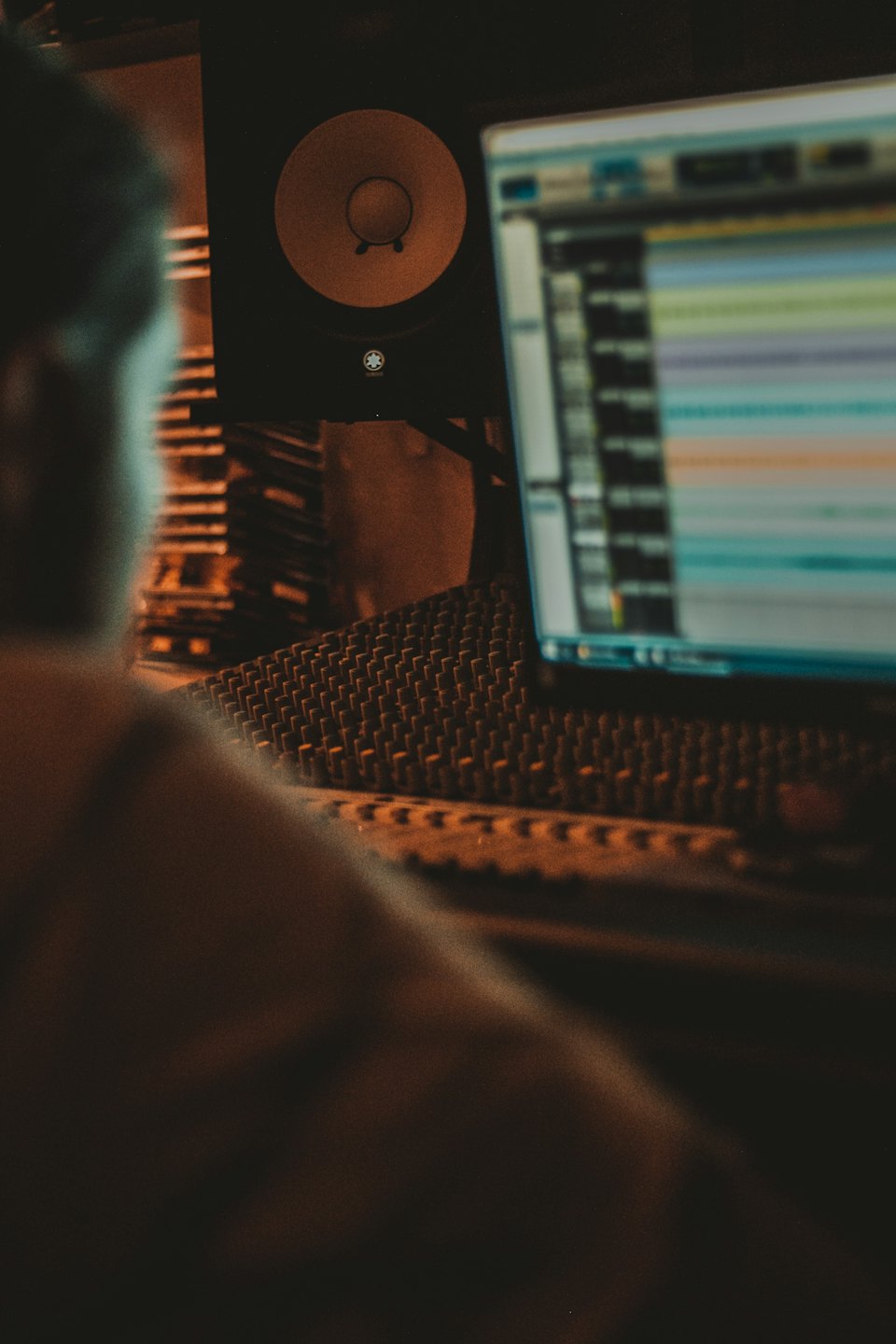 Producer adjusts audio levels on a mixing board in a studio.